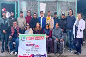 Group of individuals participating in a blood donation event, holding a banner that promotes blood donation.