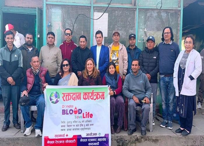 Group of individuals participating in a blood donation event, holding a banner that promotes blood donation.