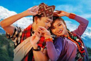 Two individuals in traditional attire dancing joyfully against a mountainous backdrop.