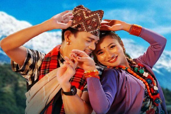 Two individuals in traditional attire dancing joyfully against a mountainous backdrop.