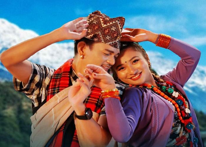 Two individuals in traditional attire dancing joyfully against a mountainous backdrop.